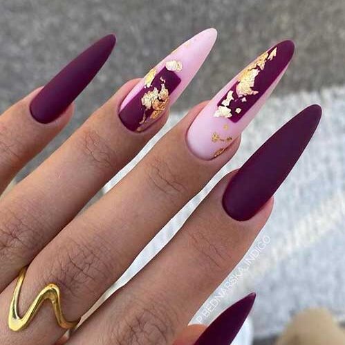 Long matte dark purple nails with two accent light pink nails adorned with gold foil are the best of November nail ideas