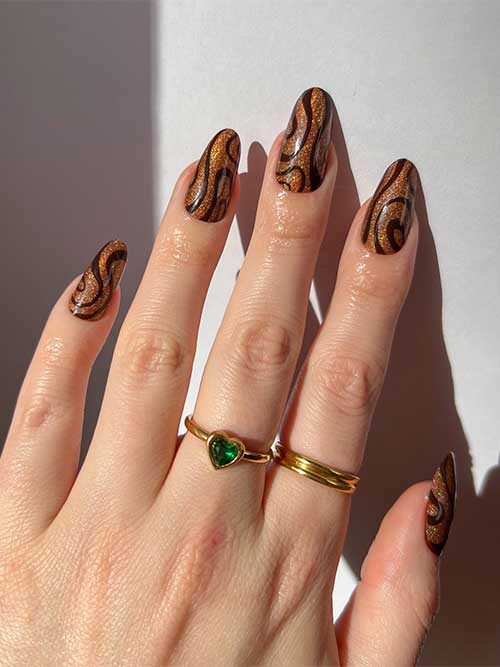Medium gold glitter nails with brown swirl nail art are one of the best November nail ideas to try