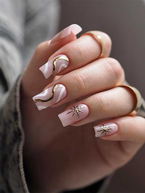 Medium square-shaped nude pink nails adorned with a gold snowflake on each nail, and two accent swirl nails