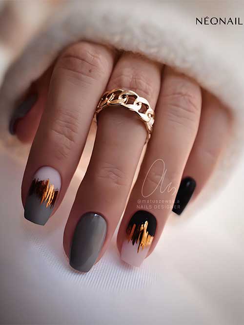 Short coffin gray and black nails adorned with gold foil decorations on two accent nails are the best of grey nail ideas 2023