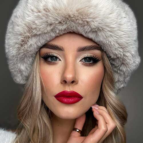 A simple Christmas party makeup look features glossy red lips, gold shimmer eyeshadow, and winged eyeliner