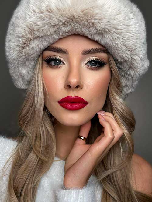 A simple Christmas party makeup look features glossy red lips, gold shimmer eyeshadow, and winged eyeliner