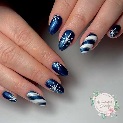 Christmas navy blue nails with white snowflakes and an accent white, navy blue, and metallic silver candy cane nail