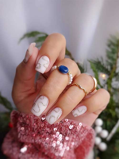 Classy short milky white nails with gold glitter swirls.