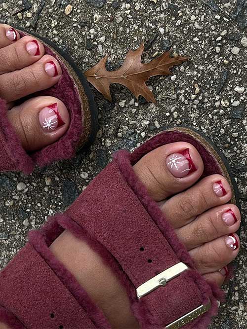 Dark red French Christmas toenails with an accent toenail adorned with a white snowflake and another with Santa’s hat