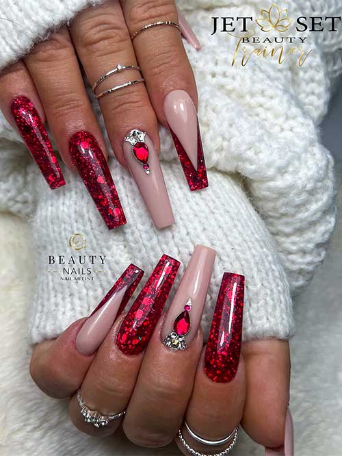 Festive long coffin-shaped red nails with encapsulated glitter flakes and an accent nude nail with red and silver rhinestones