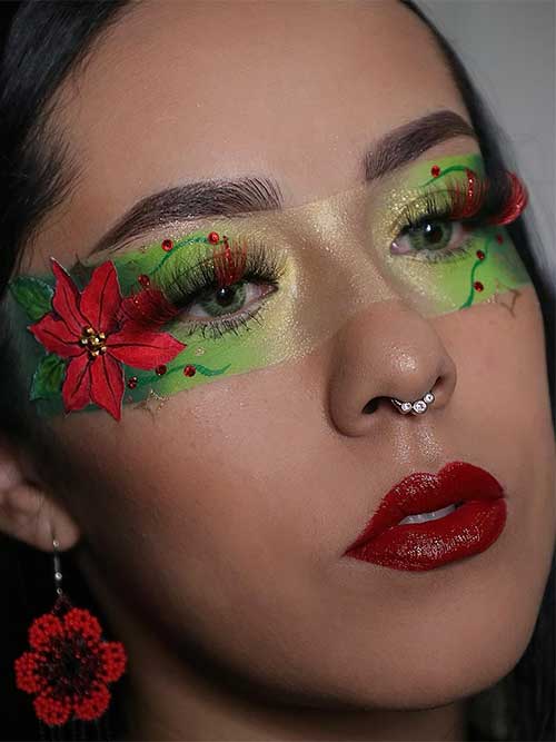 Festive red and green holly eye Christmas makeup with a big 3d red holly flower on the outer eye corner with gold rhinestones
