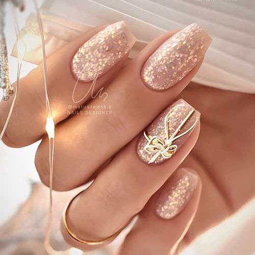 Gorgeous coffin nude Christmas nails with gold aurora flakes and a stamping gift nail art on an accent nail