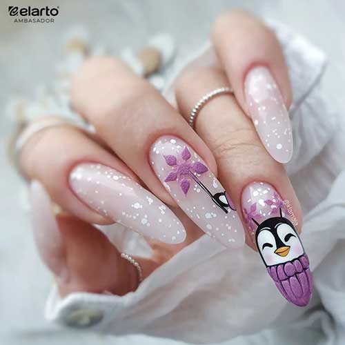 Long almond nude Christmas nails with white speckles and a penguin on an accent nail with purple snowflakes