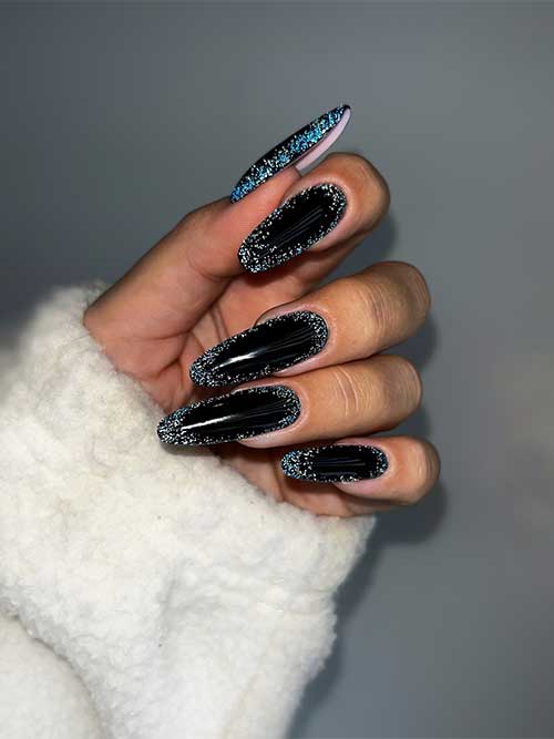 Long almond-shaped glossy black New Year’s nails with silver glitter on the nail perimeter.