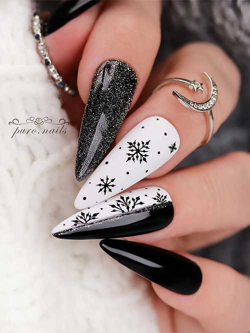 Long black and white nails with silver glitter, black snowflakes on two accent white nails one of them half white half black