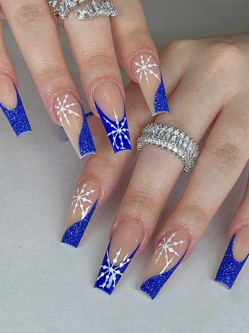Long coffin sparkly French blue Christmas nails adorned with a big white snowflake on each nail except the little nail Long coffin sparkly French blue Christmas nails adorned with a big white snowflake on each nail except the little nail