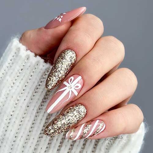 Nude sparkling Christmas nails feature snowflake nail art, tie nail art, candy cane nail art, and two gold glitter nails