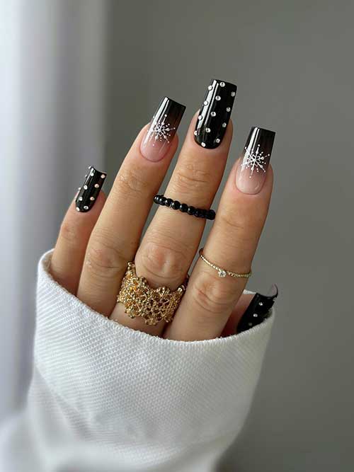 Long square-shaped glossy black winter nails with crystals and two ombre black accent nails with white snowflakes