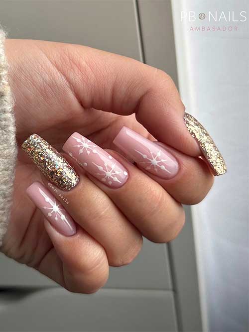 Long square-shaped nude and gold glitter sparkling Christmas nails feature three nude nails with white snowflakes
