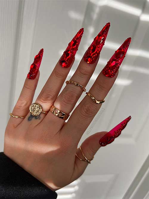 Long stiletto red New Years nails adorned with big and small red rhinestones