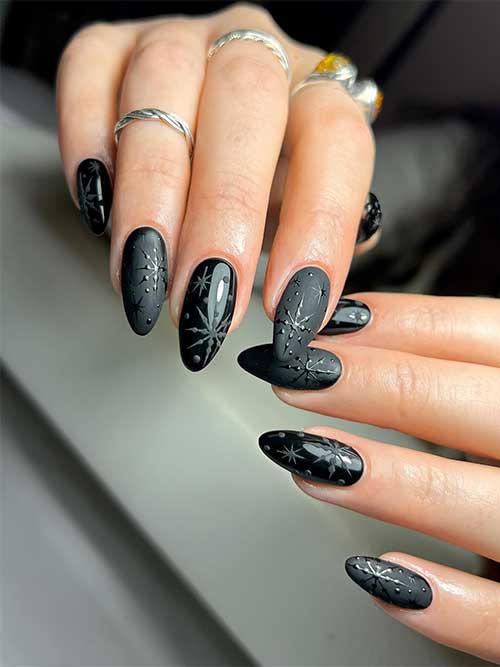 Matte and glossy long almond shaped winter black nails with snowflake nail art.