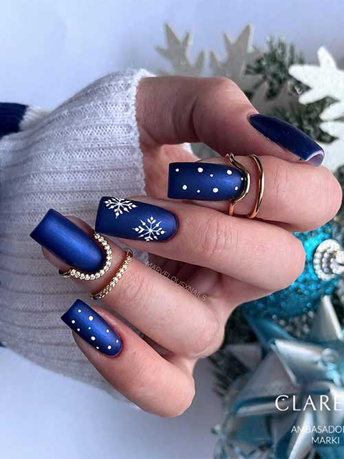 Medium square-shaped navy blue winter nails with an accent adorned with white snowflakes, and two accent white dots nails