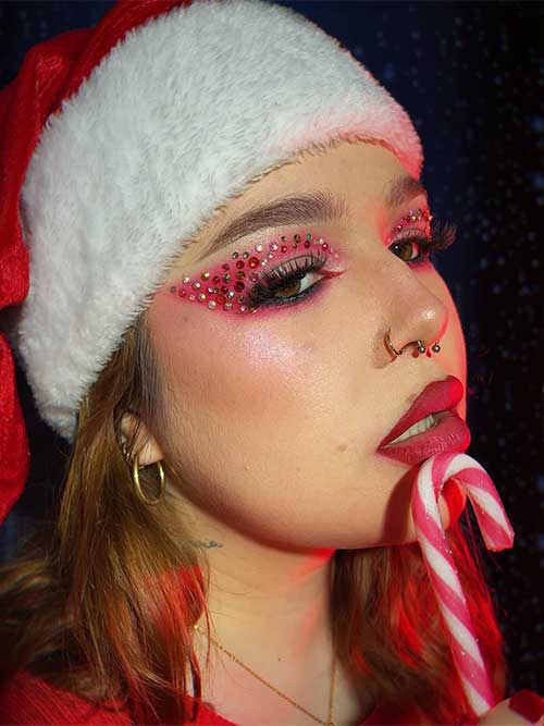 Mrs. Santa Claus's red Christmas eye makeup look is adorned with rhinestones on the eyelids. Besides, matte red lips