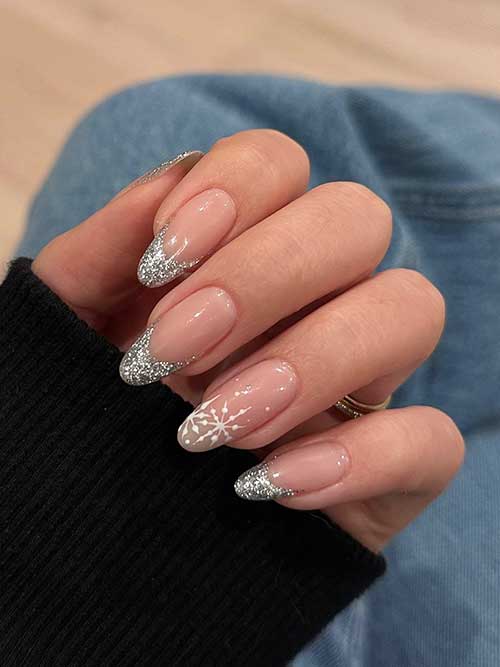 Silver glitter French New Year’s Eve nails with an accent nude nail adorned with white snowflakes on the nail tip Silver glitter French New Year’s Eve nails with an accent nude nail adorned with white snowflakes on the nail tip