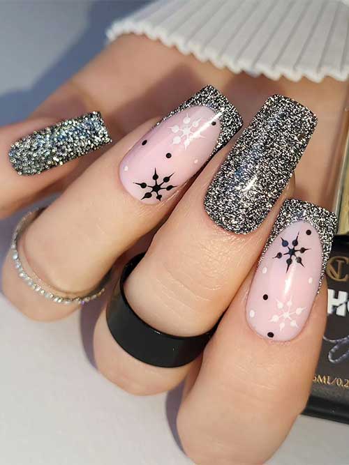Sparkling black winter nails adorned with gold glitter and two accent French tip nails with white and black snowflakes