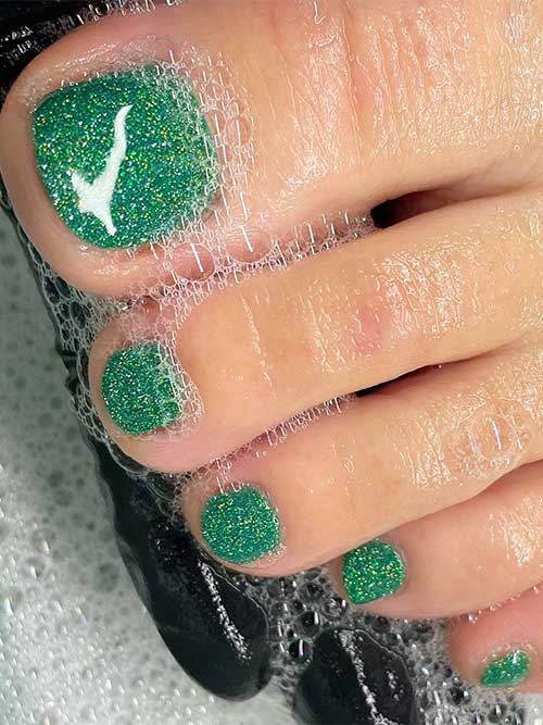 The sparkling glitter green Christmas pedicure is one of the cutest Christmas toe nail designs in 2023