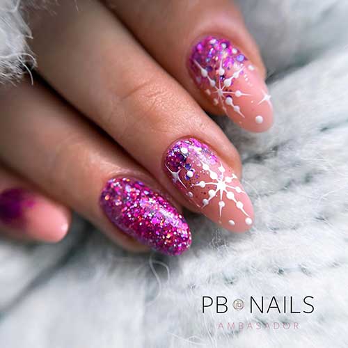 Sparkly pink Christmas nails feature nude nails adorned with white snowflakes and pink glitter above cuticles