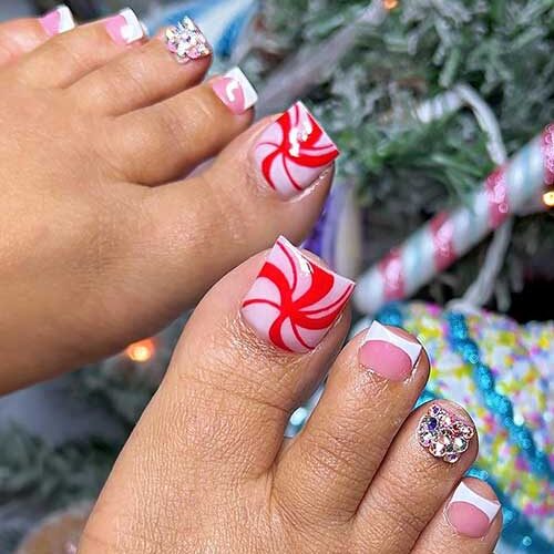 White French toenails with a candy cane big toenail and a rhinestone toe are one of the best Christmas toe nail designs