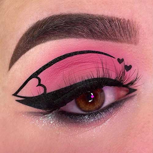 Cute matte pink eyeshadow with black winged eyeliner and black graphical eyeliner with heart shapes