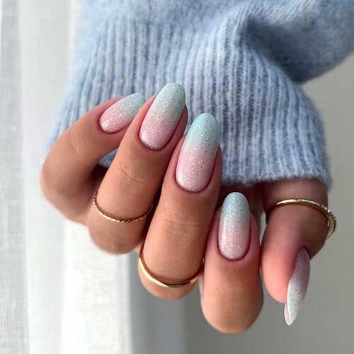 Gorgeous pink to pastel blue turquoise ombre nails adorned with silver glitter are the best of the winter nail art designs