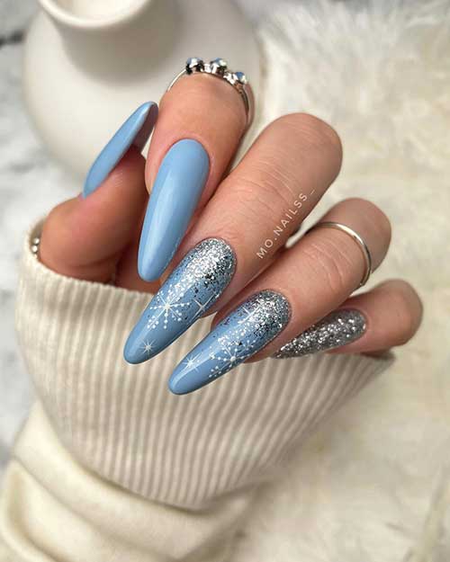 Long almond-shaped ice blue nails with two accent nails adorned with white snowflakes and silver glitter