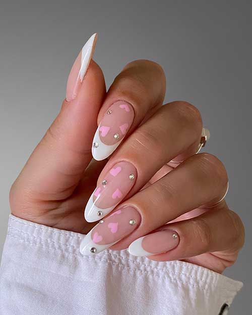 Long almond-shaped white French Valentine’s Day nails with pink hearts and silver rhinestones