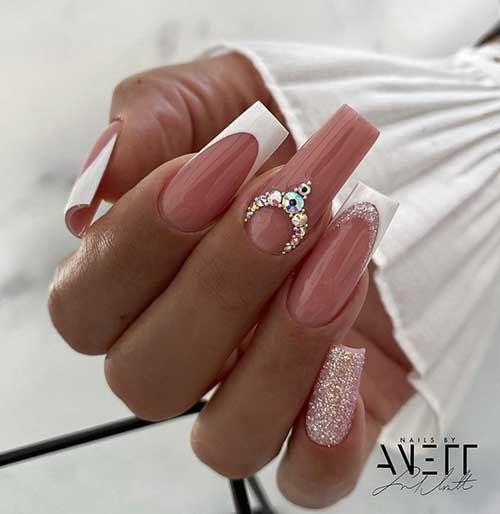 Long glossy white French tip nails with an accent nude nail adorned with gold rhinestones and another covered with glitter