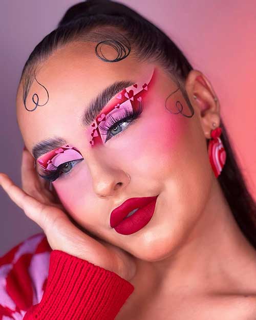 Matte Valentine's Day makeup look features red and pink eyeshadow with heart shapes and velvet red lips