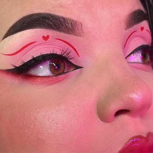 Red and pink eyeshadow look using matte pink eyeshadow on eyelids, a red graphical eyeliner with a tiny red heart shape