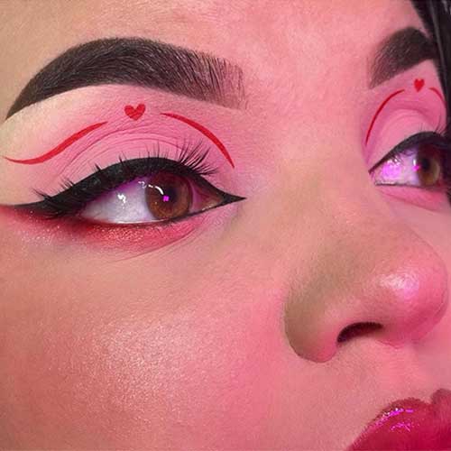 Red and pink eyeshadow look using matte pink eyeshadow on eyelids, a red graphical eyeliner with a tiny red heart shape Red and pink eyeshadow look using matte pink eyeshadow on eyelids, a red graphical eyeliner with a tiny red heart shape