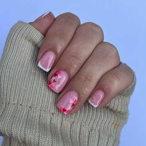 Short Valentine’s Day nails with white French tips and two nude accent nails adorned with tiny heart shapes Short Valentine’s Day nails with white French tips and two nude accent nails adorned with tiny heart shapes