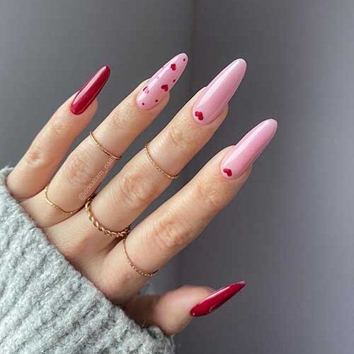 Stunning pink and red Valentine’s nails with red hearts on the pink nails. and two accent solid red nails