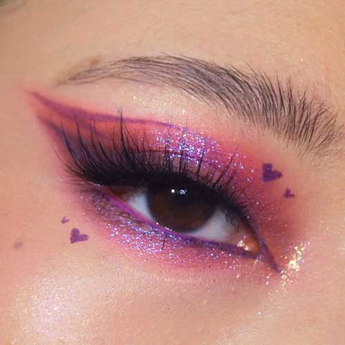Valentine's Day eye makeup features pink eyeshadow with holographic and gold glitter and purple graphical eyeliners