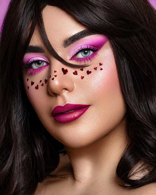 Valentine’s Day makeup look features light and hot pink eyeshadow with glossy red lips and red holographic heart glitter