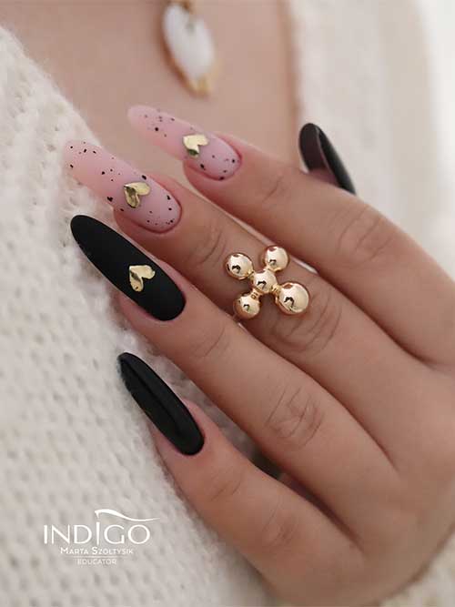 Classy almond-shaped matte black Valentine’s Day nails with two nude pink accent nails adorned with mirror gold heart shapes