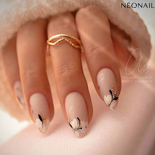 Classy almond-shaped nude nails adorned with daisy flowers adorned with gold glitter on the nail tips
