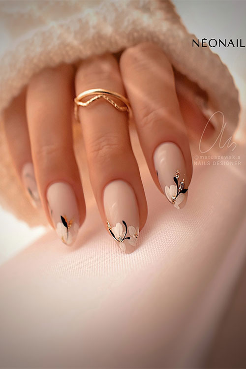 Classy almond-shaped nude nails adorned with daisy flowers adorned with gold glitter on the nail tips Classy almond-shaped nude nails adorned with daisy flowers adorned with gold glitter on the nail tips