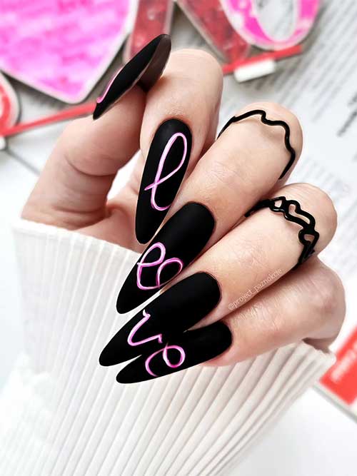 Gorgeous matte black Valentine’s Day nails adorned with LOVE letters on four fingernails using pink and white nail colors