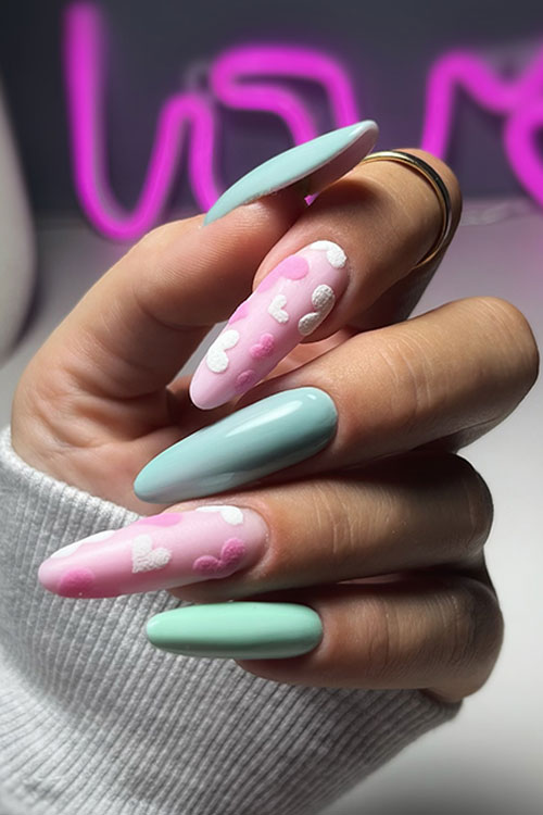 Long almond mint green and light pink pastel Valentine’s Day nails with white and candy pink hearts on the pink nails