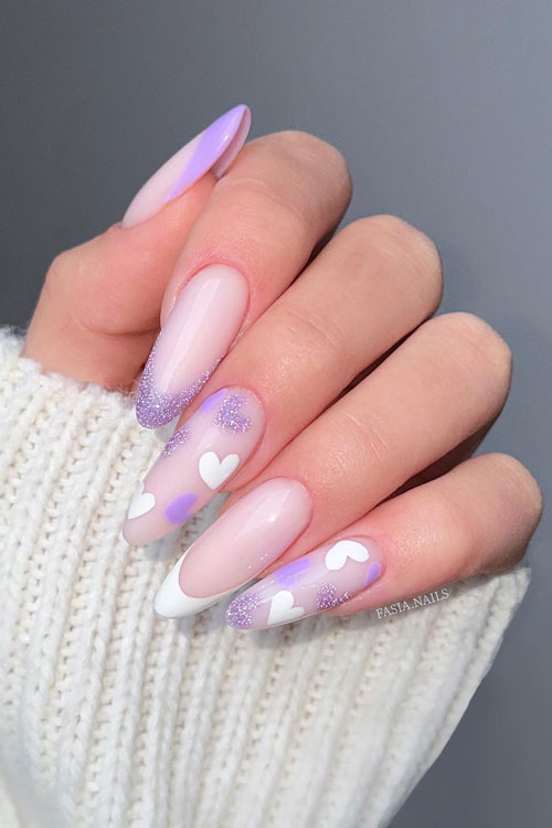 Long almond-shaped French purple pastel Valentine’s Day nails with white, lilac, glittery purple heart shapes on two accents