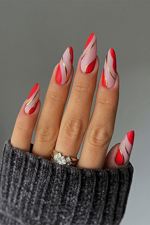 Long almond-shaped matte red negative space nails with gold swirls are one of the perfect swirl nail designs to try