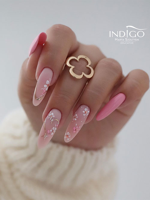 Long almond-shaped pink spring nails with three nude pink nails adorned with daisy flowers and gold decorations