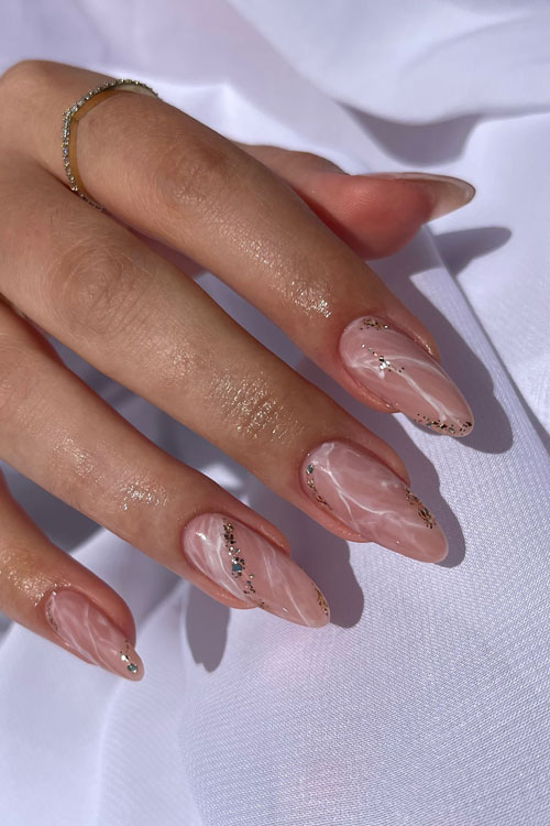 Long almond-shaped white marble nails with glitter over nude base color