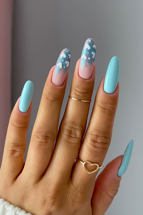 Long baby blue nails with two accent matte nude nails adorned with blue foil patches and white heart shapes